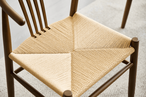 Spisebordsstol i røget bøg med lyst fletsæde. Denne stol kombinerer klassisk design med funktionalitet og komfort. Den slanke, lette træramme i røget bøg giver stolen et tidløst og sofistikeret udseende, mens det lyse fletsæde skaber en flot kontrast og tilføjer ekstra komfort og et naturligt præg. Stolen passer perfekt til moderne og nordisk inspirerede spisestuer og kan nemt integreres i både minimalistiske og mere traditionelle indretninger. Det stilrene design og den holdbare konstruktion gør denne spis